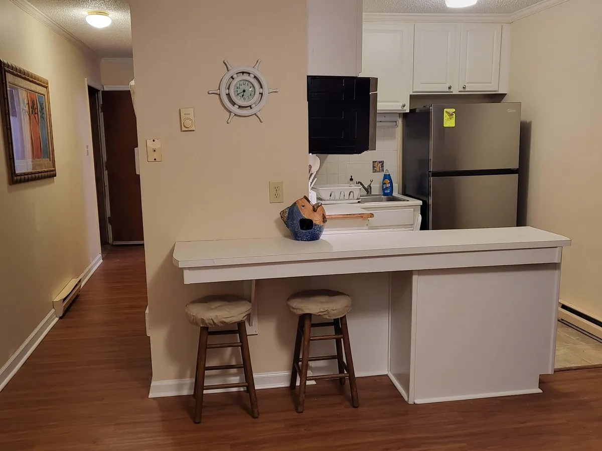 A cozy interior shot featuring a bar counter and kitchen area adorned with decorative touches. The scene suggests a space tailored for cooking and casual socializing, with warm lighting and an intimate atmosphere.