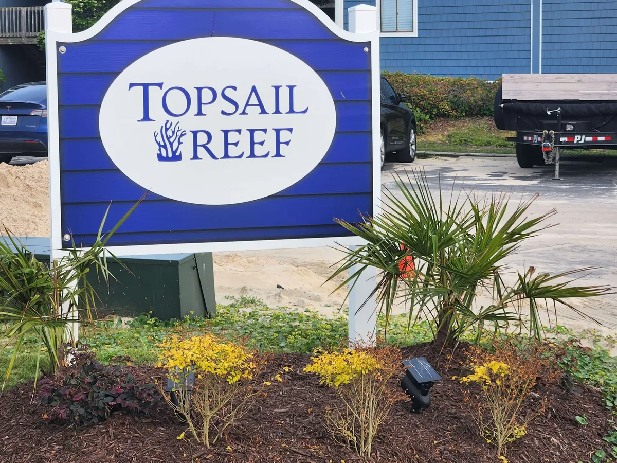The property’s welcoming entrance is marked by the distinctive Topsail Reef sign surrounded by neatly maintained landscaping. This creates a sense of arrival and sets the scene for a relaxing, well-kept getaway environment.
