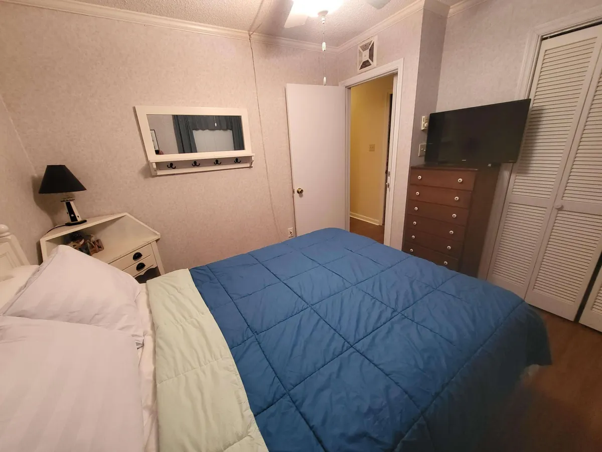This interior scene captures a warmly lit bedroom with a cozy bed, dresser, mirror, and nightstand. The inviting mood is emphasized by the soft bedding and the overall sense of comfort, making it ideal for restful nights.